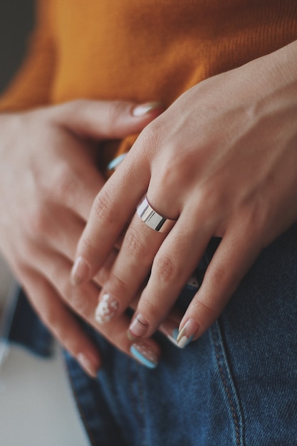 Verticale close-up die van een wijfje in een oranje overhemd is ontsproten dat een dure gouden ring draagt