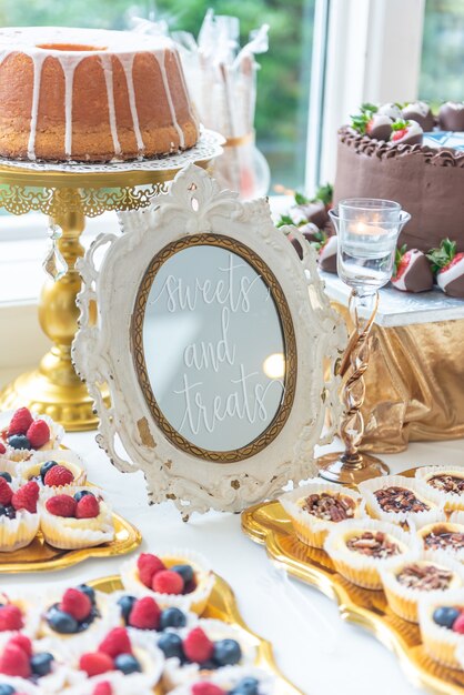 Verticale close-up shot van een dessert tafel met het schrijven "Sweets and Treats" op een frame