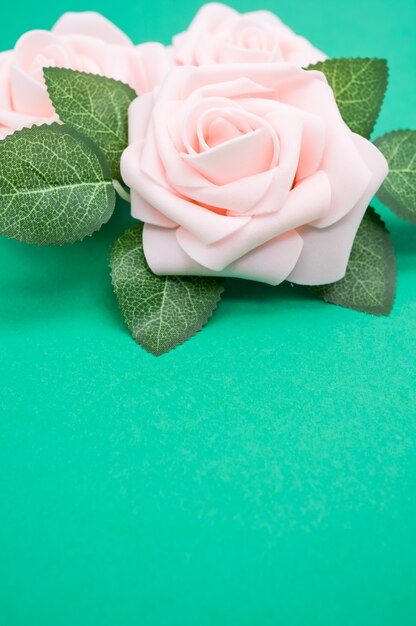 Verticale close-up shot van roze rozen geïsoleerd op een groene achtergrond met kopie ruimte