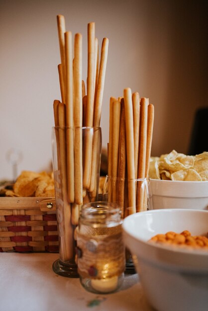 Verticale close-up shot van soepstengels in glazen containers met andere snacks op tafel