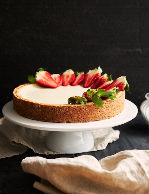 Gratis foto verticale close-up shot van strawberry cheesecake op een witte plaat en een zwarte achtergrond