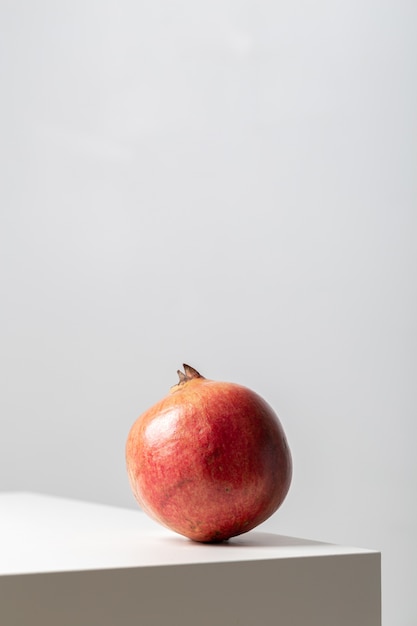 Verticale close-up van een granaatappel op de tafel onder de lichten op wit