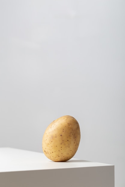Verticale close-up van een rauwe aardappel op de tafel onder de lichten op wit