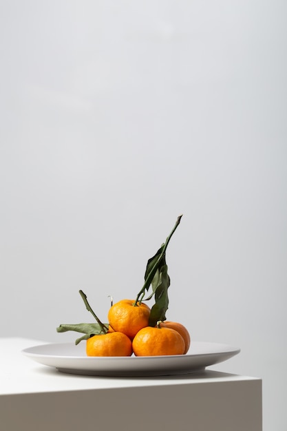 Verticale close-up van mandarijnen op een plaat op de tafel onder de lichten op wit