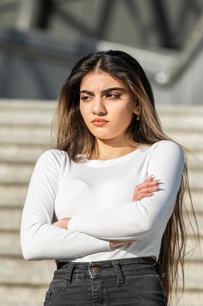 Verticale foto van een jonge dame die haar armen gekruist heeft en op de trap staat Foto van hoge kwaliteit