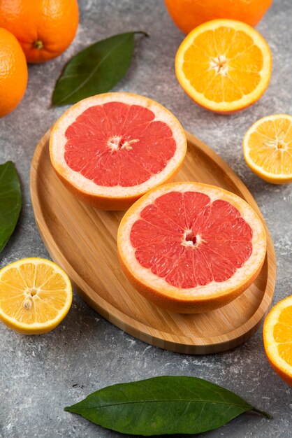 Verticale foto van half gesneden grapefruits op een houten bord over grijs oppervlak.