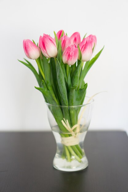 Verticale foto van tulpen in een vaas op tafel onder de lichten