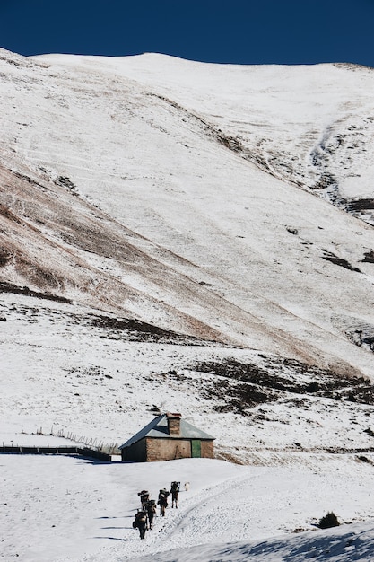 Verticale hoge hoekopname van wandelaars die de kleine hut in de besneeuwde bergen naderen