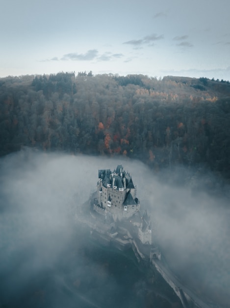 Verticale luchtfoto van het kasteel Eltz omgeven met wolken en bomen in Duitsland