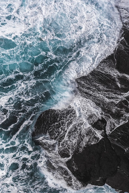 Verticale luchtfoto van zee golven raken de rotsen