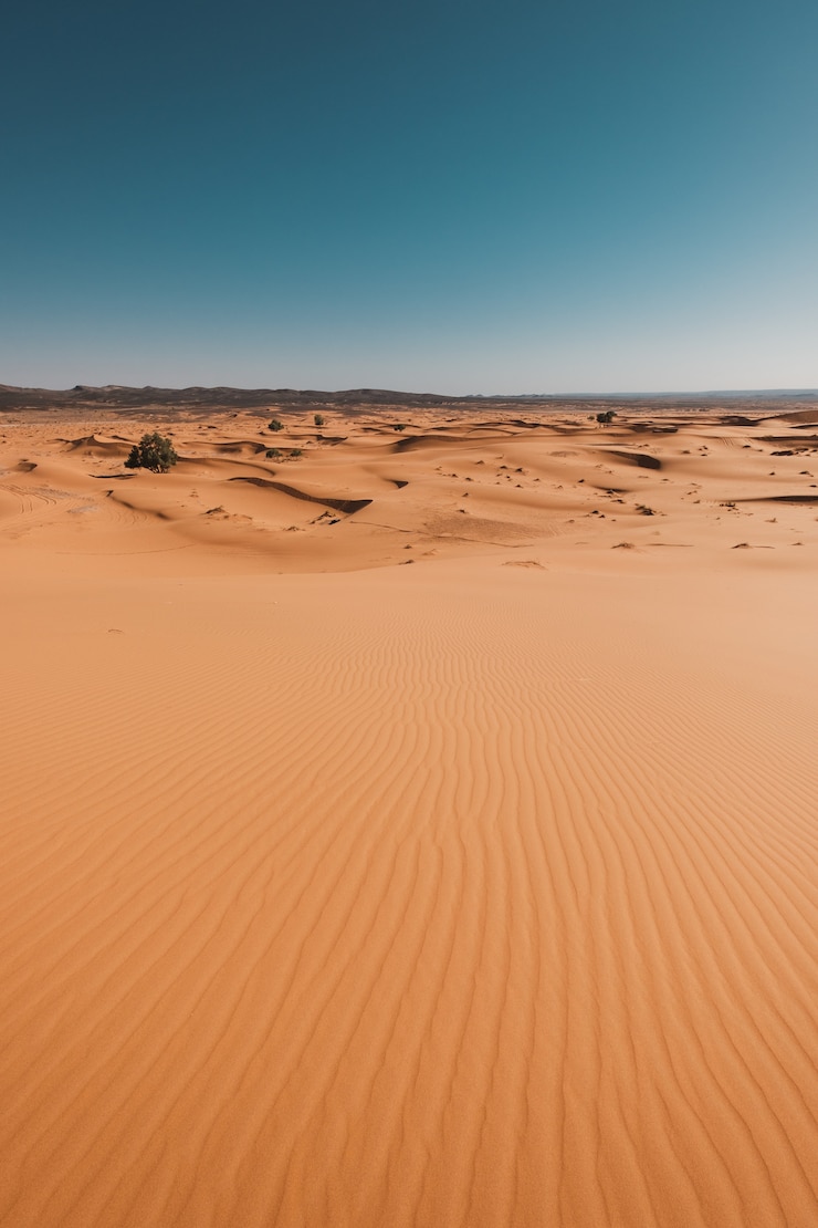 Gratis Foto verticale opname van de adembenemende woestijn onder de blauwe hemel gevangen in marokko