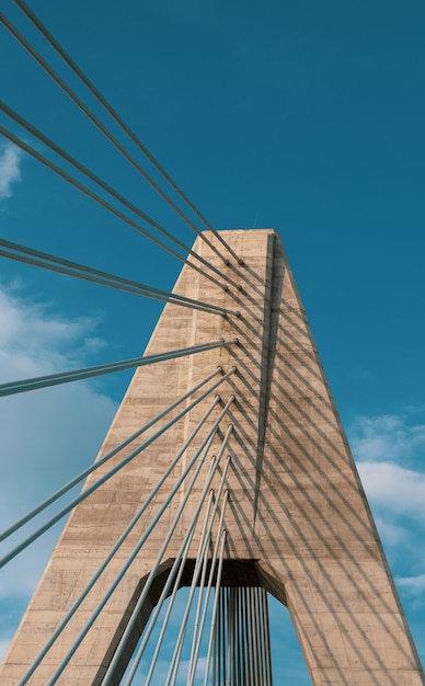 Gratis foto verticale opname van een brug onder een bewolkte blauwe hemel