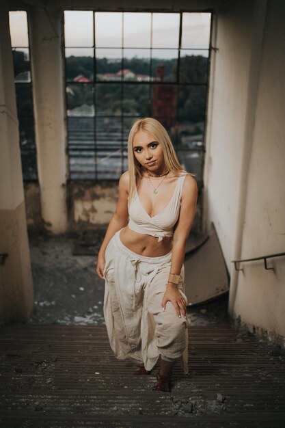 Verticale opname van een jonge sexy vrouw die poseert in een verlaten gebouw