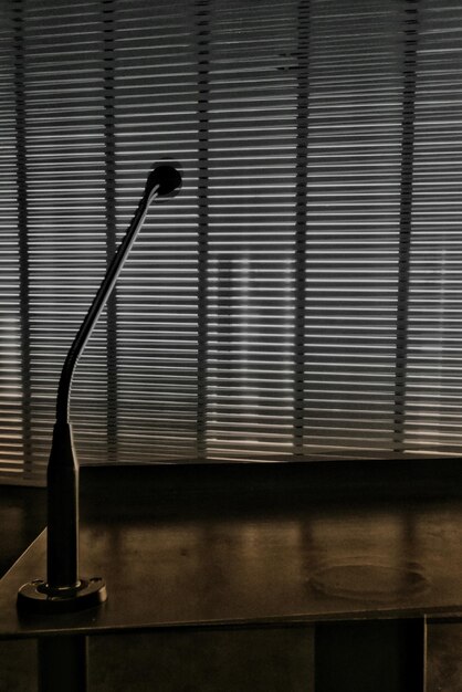 Verticale opname van een lamp op een kantoortafel en ramen met jaloezieën op de achtergrond