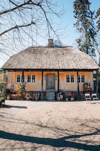 Gratis foto verticale opname van een mooi dorpshuis tussen de bomen, vastgelegd op een zonnige dag