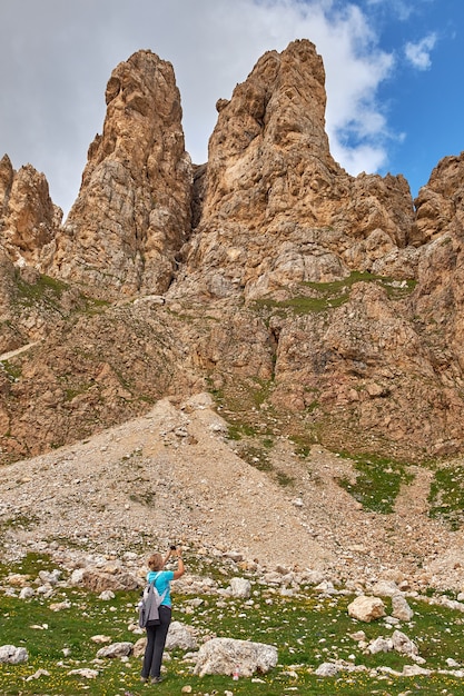 Gratis foto verticale opname van een toerist die een foto neemt van hoge rotswanden in italië