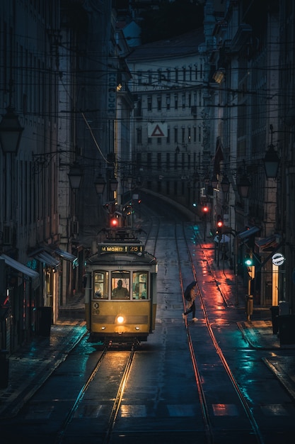 Verticale opname van een tram terwijl deze 's nachts door de gebouwen van een stad gaat