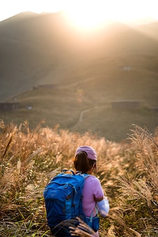 Verticale opname van een vrouw met een grote rugzak die bij zonsondergang in de bergen wandelt