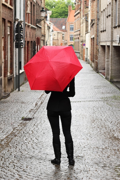 Gratis foto verticale opname van een vrouw met een rode paraplu in de straat