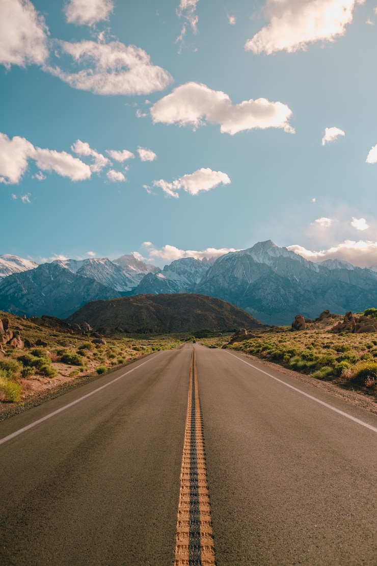 Gratis Foto verticale opname van een weg met de prachtige bergen onder de blauwe lucht, vastgelegd in californië