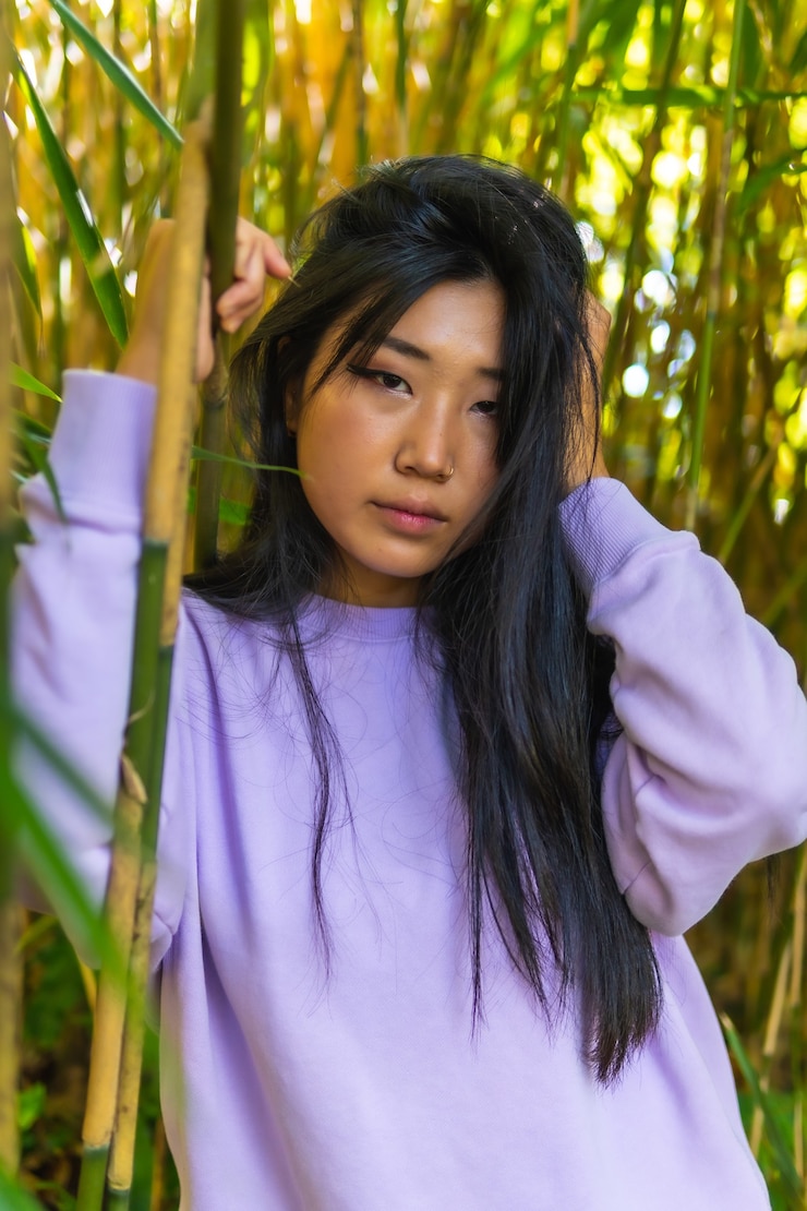 Gratis Foto verticale opname van het portret van een mooi chinees meisje, poserend in de buurt van bamboeplanten