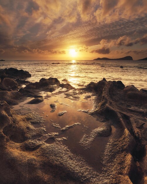 Verticale opname van het rotsachtige strand en de oceaan tijdens zonsopgang