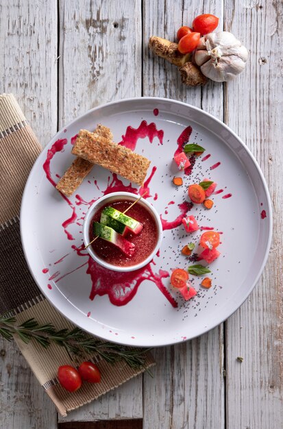 Verticale opname van stukjes brood, gesneden cherrytomaatjes en stukjes watermeloen in een saus op een bord