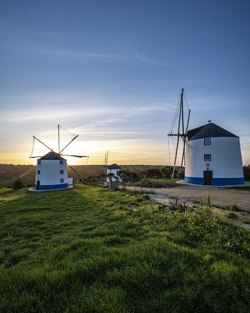 Verticale opname van windmolens met een zonsopgang in een heldere blauwe lucht op de achtergrond