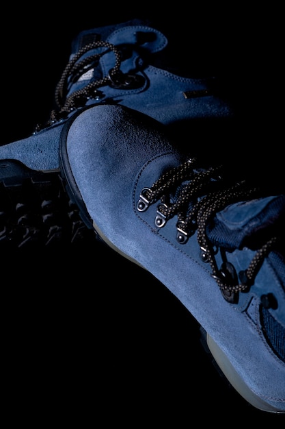 Verticale shot van blauwe winter trekking laarzen op zwarte achtergrond