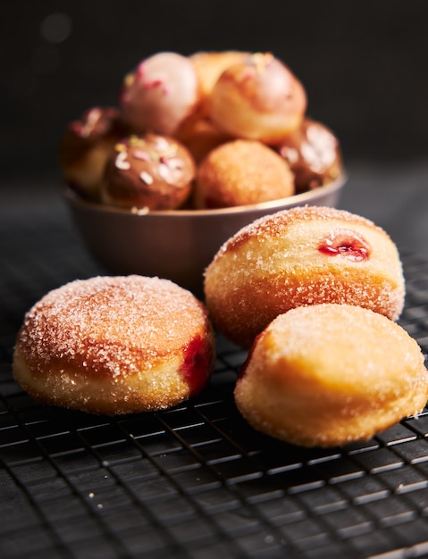 Gratis foto verticale shot van gebakken donuts met suiker en room op een zwarte tafel