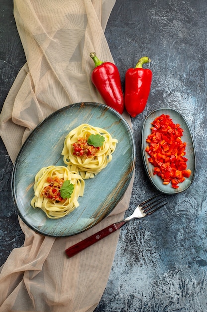 Verticale weergave van een blauw bord met heerlijke pastamaaltijd geserveerd met tomaat en vlees op een bruine kleurhanddoek voor het diner, de ingrediënten ervan