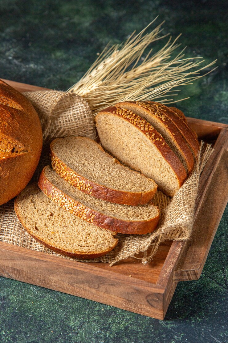 Gratis Foto verticale weergave van geheel en vers zwart brood op handdoek in een bruine houten doos op donkere mix kleuren oppervlak