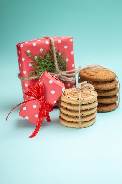 Verticale weergave van gestapelde verschillende heerlijke koekjes en rode geschenkdozen op pastelgroene achtergrond