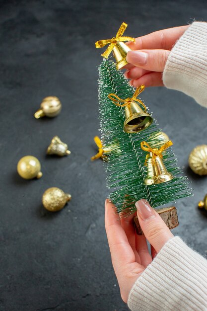 Verticale weergave van hand met kerstboom en decoratie accessoires op donkere achtergrond