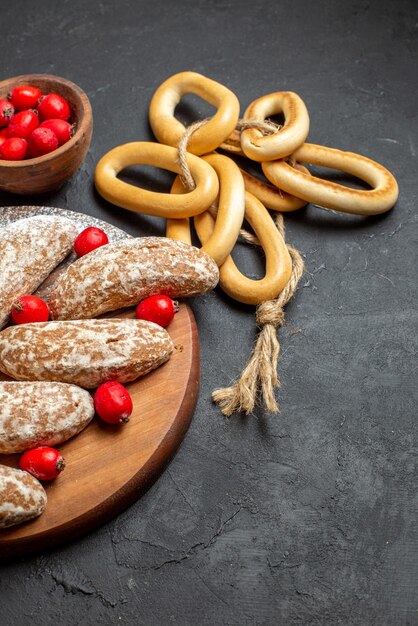 Gratis foto verticale weergave van heerlijke banaan koekjes met fruit op bruin houten dienblad op zwarte tafel