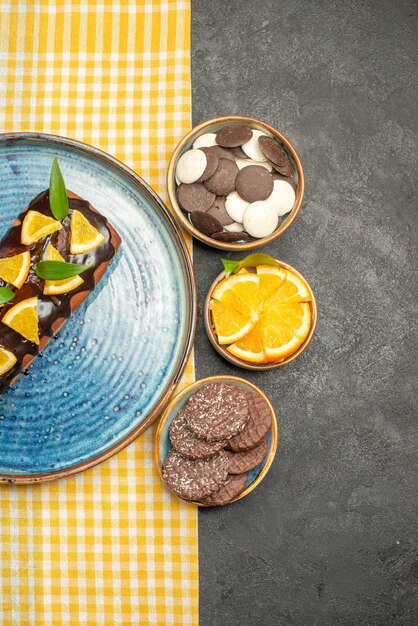 Verticale weergave van heerlijke cake op gele gestripte handdoek en koekjes op zwarte tafel