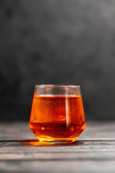 Verticale weergave van heerlijke jus d'orange in een glas op donkere achtergrond