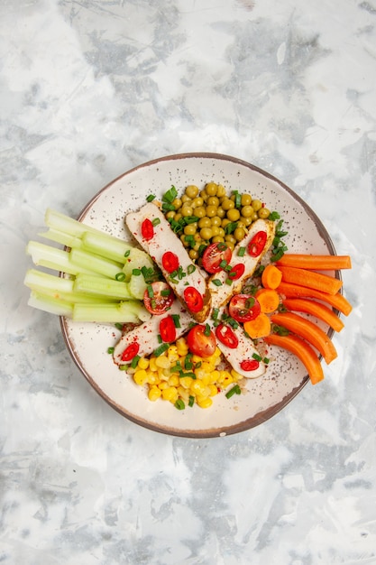 Verticale weergave van heerlijke veganistische salade op een plaat op een gekleurd wit oppervlak