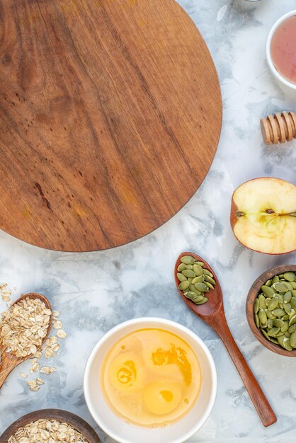 Verticale weergave van houten ronde plank en ingrediënten voor de gezonde voeding op een gebeitste witte achtergrond