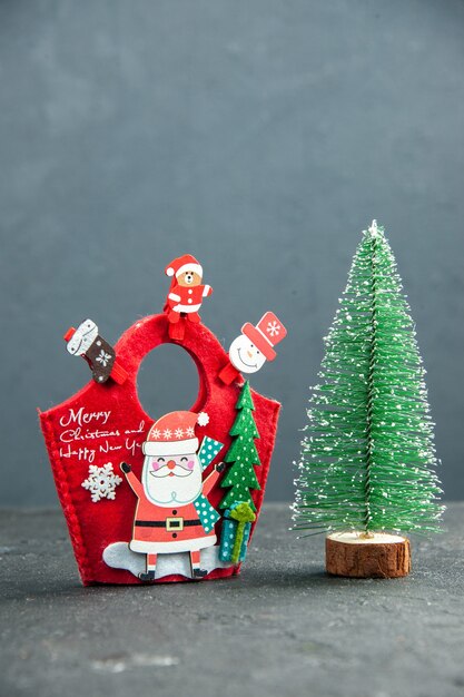 Verticale weergave van kerststemming met decoratieaccessoires op nieuwjaarsgeschenkdoos en kerstboom op donkere ondergrond