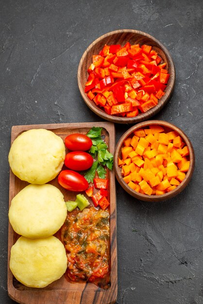 Verticale weergave van koken met verse groenten en gehakte voedingsmiddelen op zwarte tafel