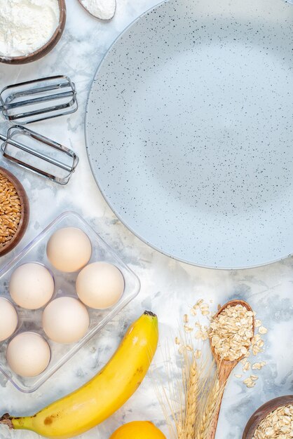 Verticale weergave van lege grijze plaat en ingrediënten voor de gezonde voeding op ijsoppervlak