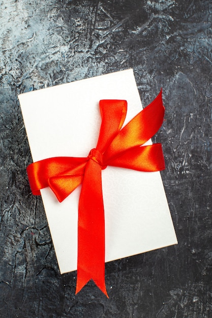 Verticale weergave van prachtig verpakte geschenkdozen vastgebonden met rood lint op donker