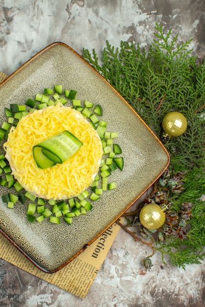 Verticale weergave van smakelijke salade geserveerd met gehakte komkommer en mesvork op een oude krantendecoratie-accessoires op gemengde kleurachtergrond