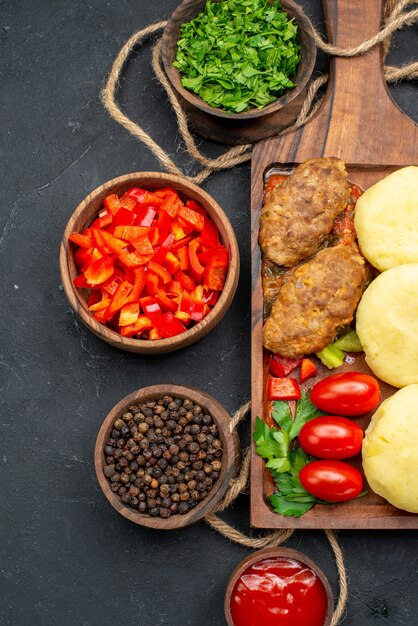 Verticale weergave van smakelijke schnitzels gehakte groenten Groenen voor het diner op donker