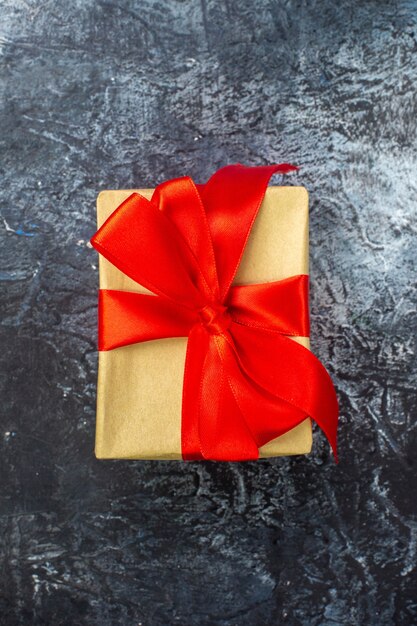 Gratis foto verticale weergave van speciaal cadeau met rood lint op donkere ondergrond