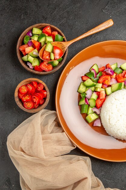 Verticale weergave van veganistisch diner met rijst en verschillende soorten groenten op zwart