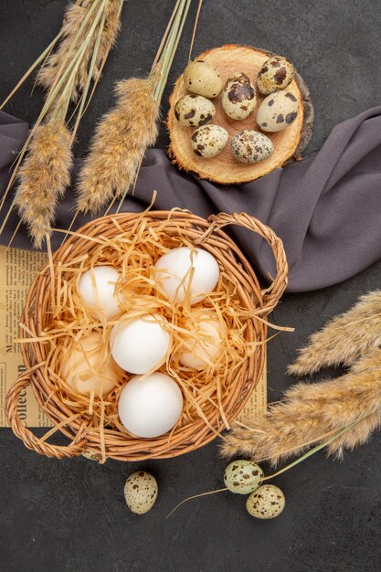 Gratis foto verticale weergave van verschillende biologische eieren op een oude krant op zwarte handdoek op donkere achtergrond