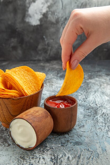 Gratis foto verticale weergave van zelfgemaakte heerlijke knapperige chips in een bruine kom mayonaiseketchup op grijze achtergrond