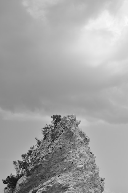 Verticale zwart-wit foto van een rotsformatie met wolken